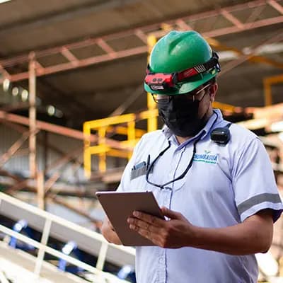 Colaborador con casco revisando una tableta en la planta