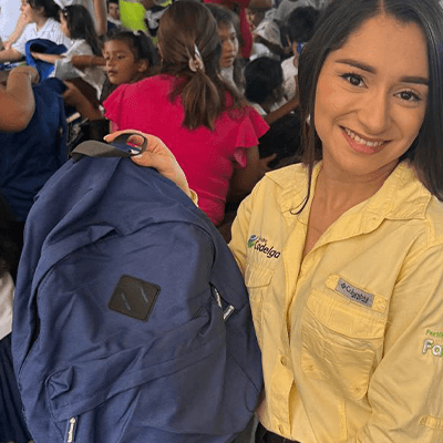 Colaboradora de Cadelga muestra una mochila durante una entrega de útiles escolares
