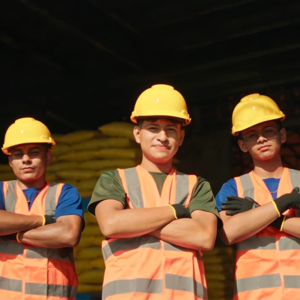Tres colaboradores de almacén con cascos y chalecos de seguridad